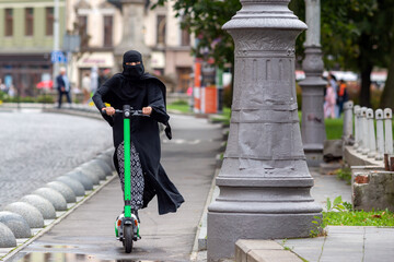 Muslim woman in a burqa rides a scooter in the city.