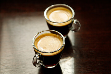 two glass coffee cup with espresso near the window in morning on dark background