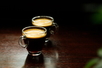 two glass coffee cup with espresso near the window in morning on dark background