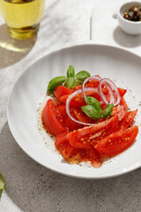 Salad with tomatoes and basil with oil in bottle on white board on white background
