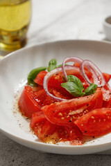 Salad with tomatoes and basil with oil in bottle on white board on white background