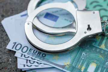 handcuffs lie on a pack of one hundred euros