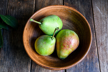 Home harvest fresh pears in earthenware on a wooden table. View from above.