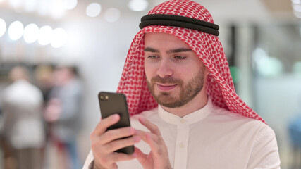 Portrait of Serious Arab Businessman Browsing Internet on Smartphone