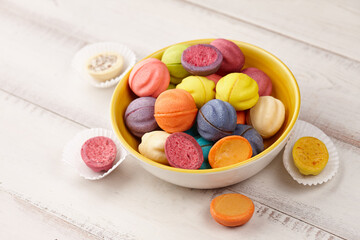 Colorful shortbread cookies in bowl on white wooden table