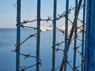 Barriers and barbed wire at sea prevent access to the pier with ships.
