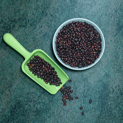 black beans in a ceramic bowl and a plastic spoon on a dark marble surface