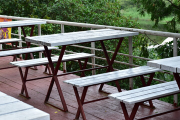 The picture shows the tables and benches of an open-air cafe in white.