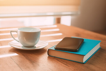 Cup of coffee, mobile smart phone and a book on the table in morning