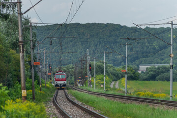 Passenger train with red electric locomotive and passenger coaches in summer