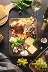 Cheese platter with grapes, nuts, figs on a brown background. Top view. Festive gourmet appetizer...