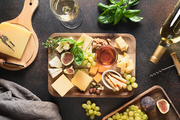 Cheese platter with grapes, nuts, figs on a brown background. Top view. Festive gourmet appetizer...