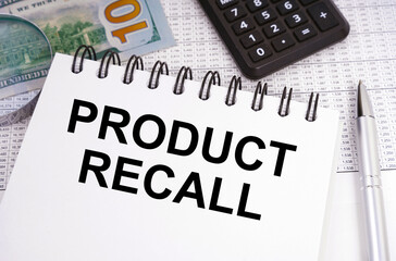 On the table there is money, a calculator and a notebook with the inscription - PRODUCT RECALL