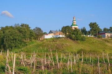 Countryside landscape with abandoned aged Orthodox Church on the hill in Russia hinterland. Panoramic scenic view from dried swamp valley to rural old orthodox authentic church on the hill in village.