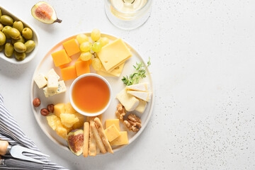Cheese platter with grapes, nuts, figs on a white background. Top view. Copy space. Festive gourmet snack.