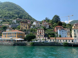 Fototapeta na wymiar Skyline of Argegno town with houses on hills and mountains. Landscape of Como Lake (Lago di Como). View from the boat of cityscape and nature. Argegno, Como Lake, Lombardy, Italy