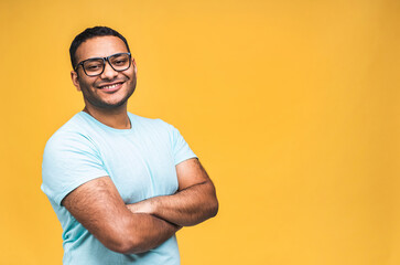 Portrait of a cheerful young african american indian black man standing isolated over yellow background.