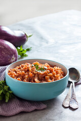 Eggplant caviar in blue bowl and fresh vegetables on background