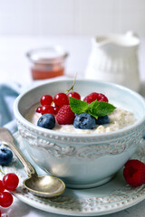 Oatmeal porridge with fresh berries and maple syrup for a breakfast.