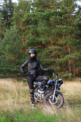 Naklejka premium a woman on a motorcycle in nature. motorcyclist walk through the forest