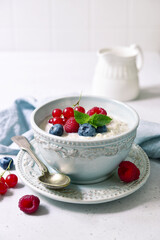 Oatmeal porridge with fresh berries and maple syrup for a breakfast.