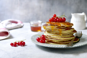 Delicious hot pancakes with fresh berries and maple syrup for a breakfast.
