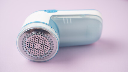 Small fabric shaver on purple background. Handed lint remover. Clothes shaver device