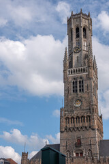 Fototapeta na wymiar Brugge, Flanders, Belgium - August 3, 2021: Brown stone Tower of Halletoren Belfry against blue cloudscape.