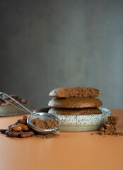 Gluten free, Vegan Homemade Chocolate Chip cookies from cocoa in a ceramic bowl.Organic product:cocoa powder, beans on a beige,dark background.Delicious healthy eat and cocoa products, during dessert