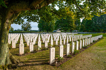 A mature tree guards the neatly lined rows of gravestones in Bayeux War Cemetery in France,...