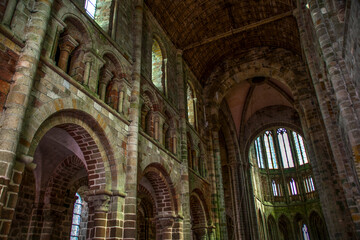 An interior view of the vast walls and arched doorways and ceilings in the medieval abbey of Mont Saint Michel in France.
