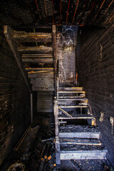 Burnt wooden house interior. Charred stairs and walls. Consequences of fire