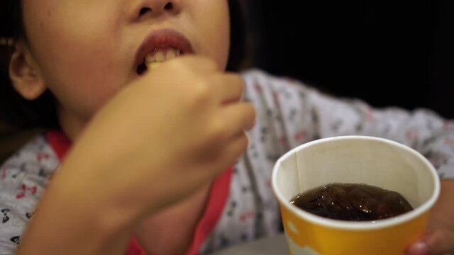 Chinese girl soak French fries into coke and then eat