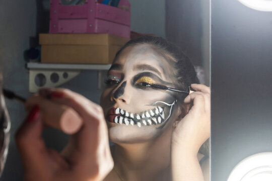 Close-up of a beautiful girl lifting her eyelashes, halloween makeup done in her room.