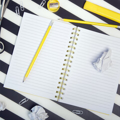 Education concept: notebook with pencils and crumpled paper balls on black and white striped...