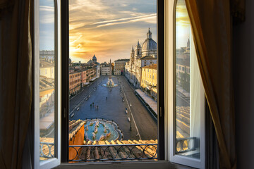 View through an open window of a room overlooking Piazza Navona at sunset in Rome, Italy.