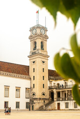 A view at the Tower and Paco das Escolas Square of University of Coimbra through the green tree leaves - Selective focus, Portugal