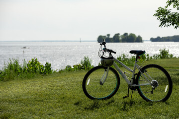 Fototapeta na wymiar Vue d'une bicyclette stationnée sur le bord de l'eau en été avec vue sur le fleuve