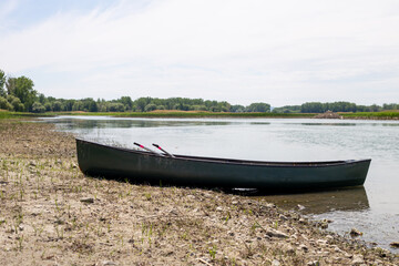 canoe vert sur le bord d'une rivière calme lors d'une journée ensoleillée d'été avec les rames