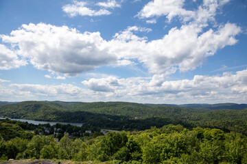 vue d'une vallée avec des arbres verts en plein jour d'été
avec des nuages sur un ciel bleu et une rivière au loin