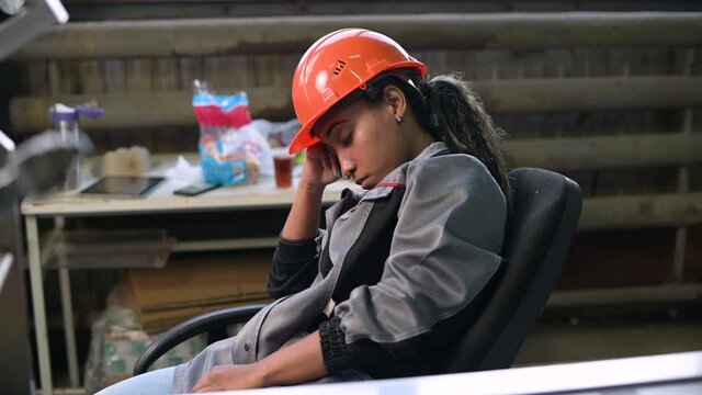 A young black female worker in heavy production fell asleep at her workplace. Violation of working conditions and overwork exhausting workers, harsh working conditions