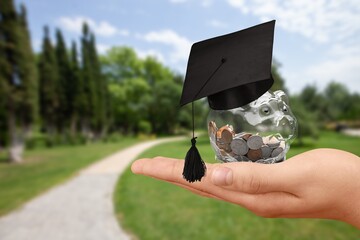 Graduation hat on a glass jar with money in hand