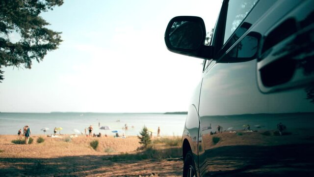 Parked van reflects sunbathing and swimming people on the beach. Summer vacations travel time