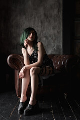 Stylish young woman with green in a black dress. Portrait of a beautiful girl with green hair 