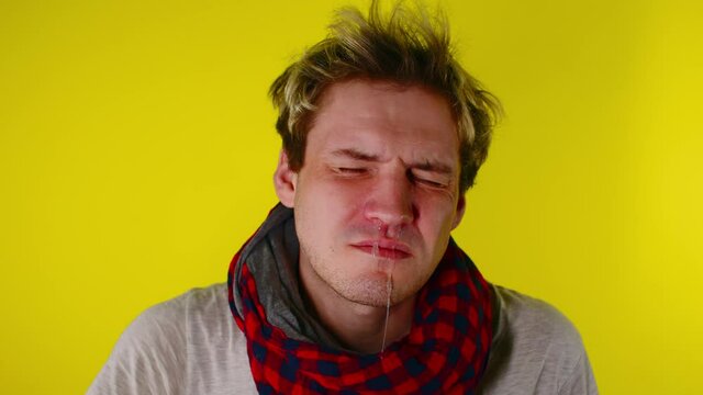 The man has a runny nose. Snot flows from the nose. A man has a cold, he has a runny nose