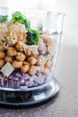 food processor with falafels ingredients inside including chickpeas onion cilantro garlic and sesame seeds, simple ingredients concept