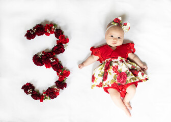 Little newborn baby girl in red dress. 3 month old baby
