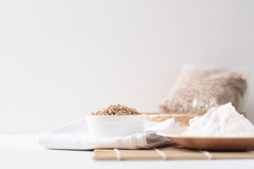 Whole wheat grains and wheat flour on white background. Natural organic products, healthy baking ingredients.