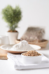 Whole wheat grains and wheat flour on white background. Natural organic products, healthy baking ingredients.