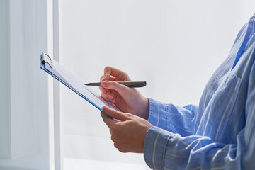 Faceless female person writing on clipboard with pen, secretary or inspector idea, formal clothes....
